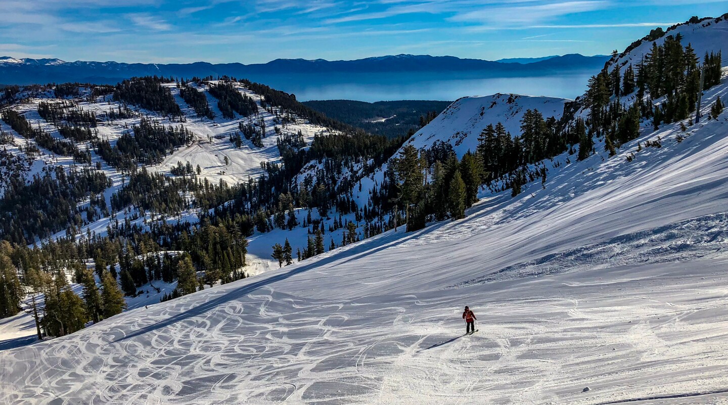 Lone skier on wide slope, with Lake Tahoe in background