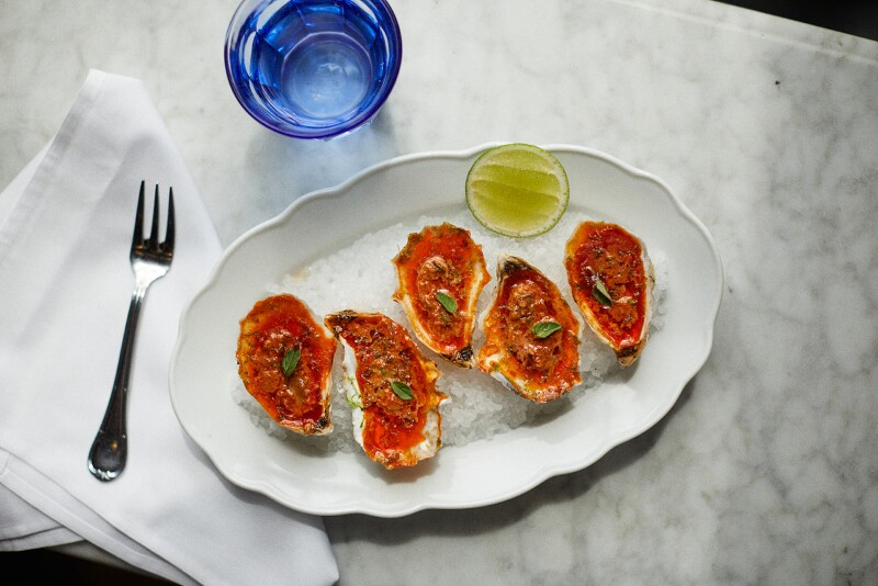 A plate of oysters and a glass of water on a white restaurant table