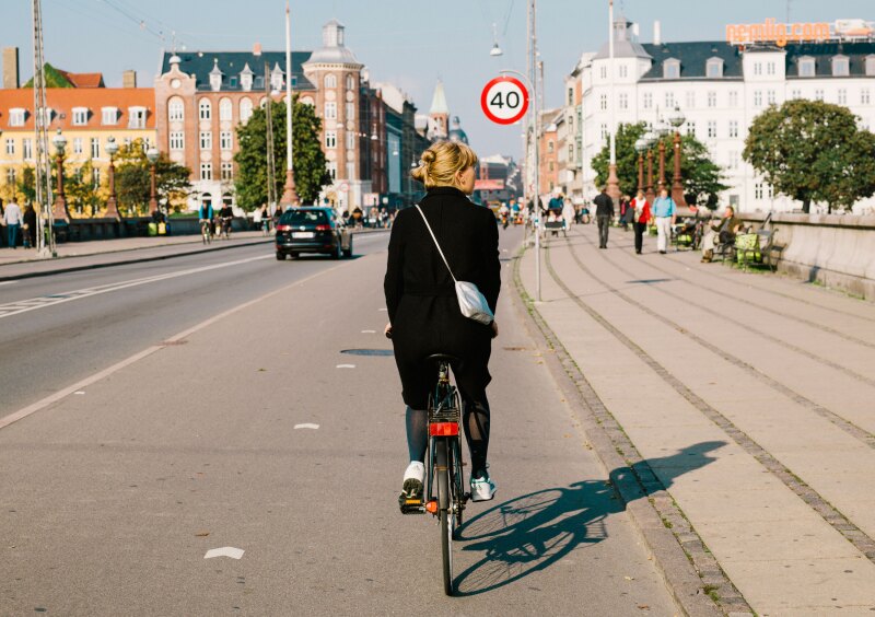 rear shot of a woman in black riding a bicycle across a bridge in Copenhagen, Denmark