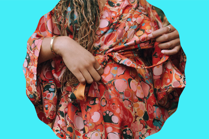 Closeup of person wearing silk bathrobe with marbled pattern mostly in shades of pink and coral