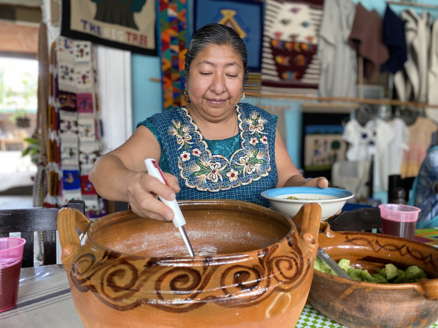 A woman serving traditional Oaxacan cuisine from an earthen pot.