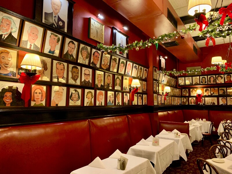 Red leather banquettes under rows of caricatures