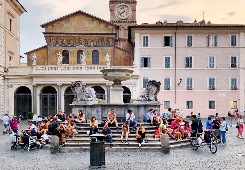 Piazza di Santa Maria in Trastevere, with people sitting on steps around fountain