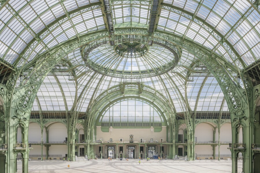 Empty interior of the Grand Palais, with arched glass ceiling and ornate, pale green metal supports