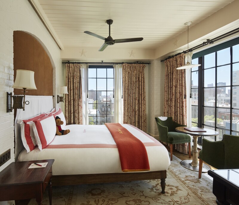 This guest room in the Bowery Hotel in New York City has a red-and-white bedspread and floor-to-ceiling windows,
