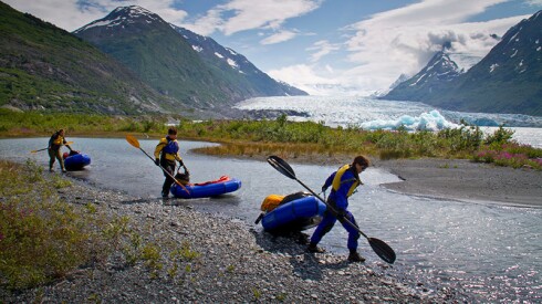 Three women pull their packrafts along the shore of Spencer Glacier Lake, Kenai Mountains, Southcentral Alaska, Summer