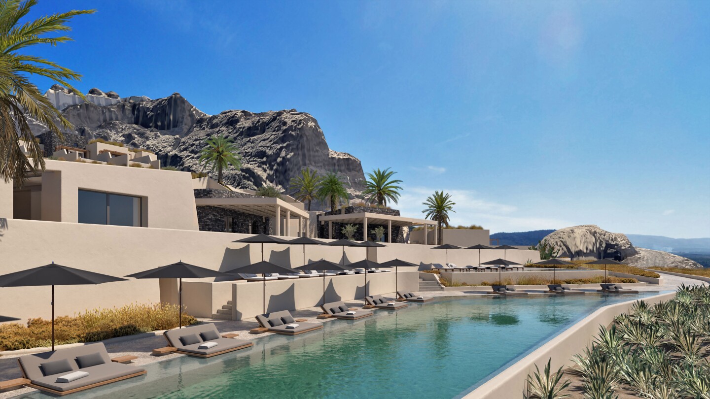 The main pool at Santo Mine Oia Suites in Greece is flanked by gray chaise longues.