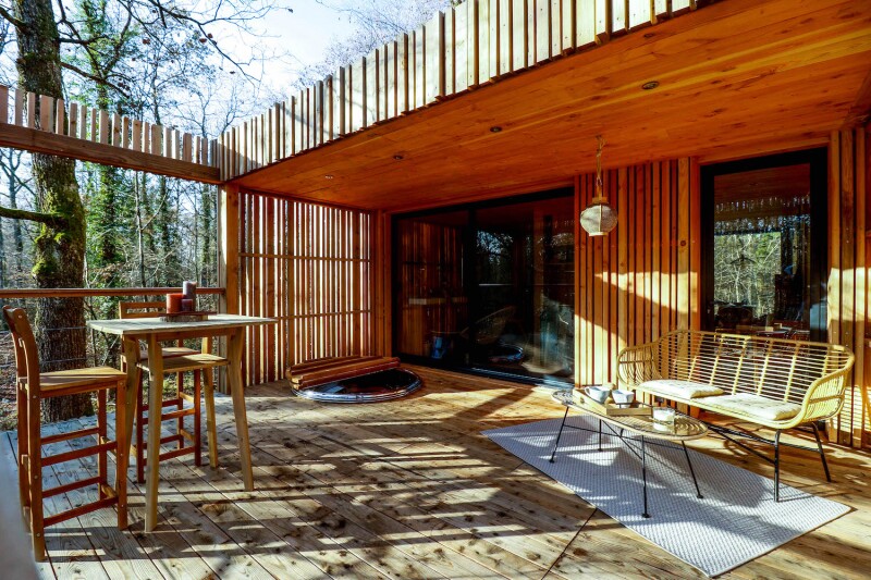 Sunny deck of a tree house at the Loire Valley Lodges, with seating and small tables