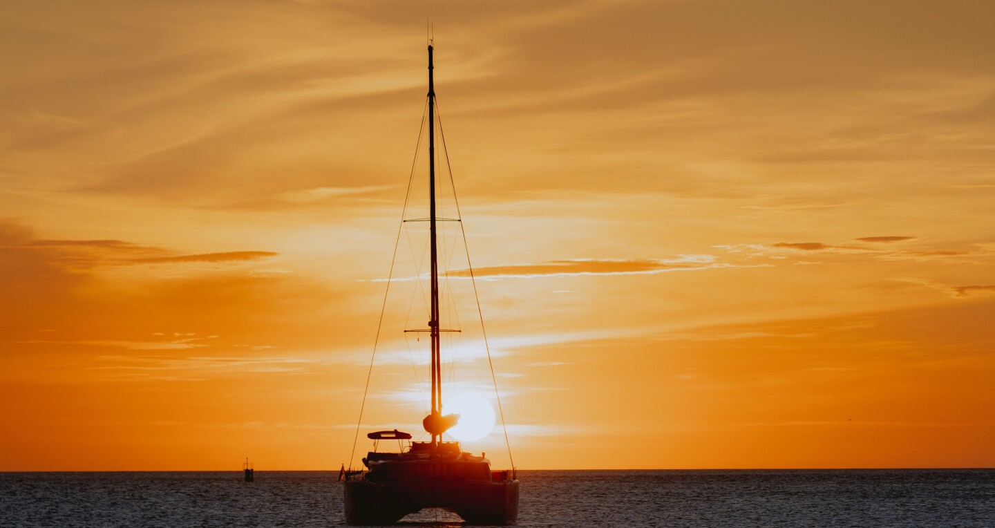 A silhouette of luxury catamaran on the ocean at sunset in Aruba.