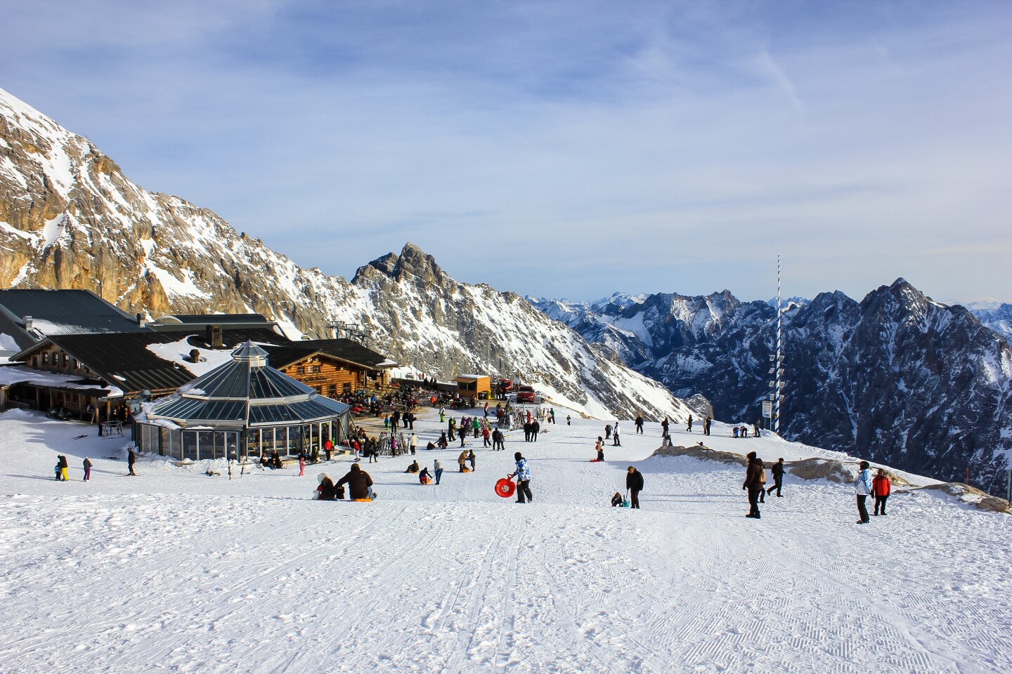 People near a wooded hut on a snow-covered mountain.