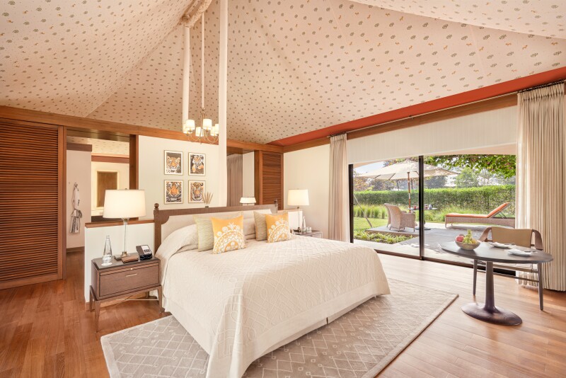 The interior of tented guest room, with canvas ceiling, wood floors, and large glass doors leading to veranda