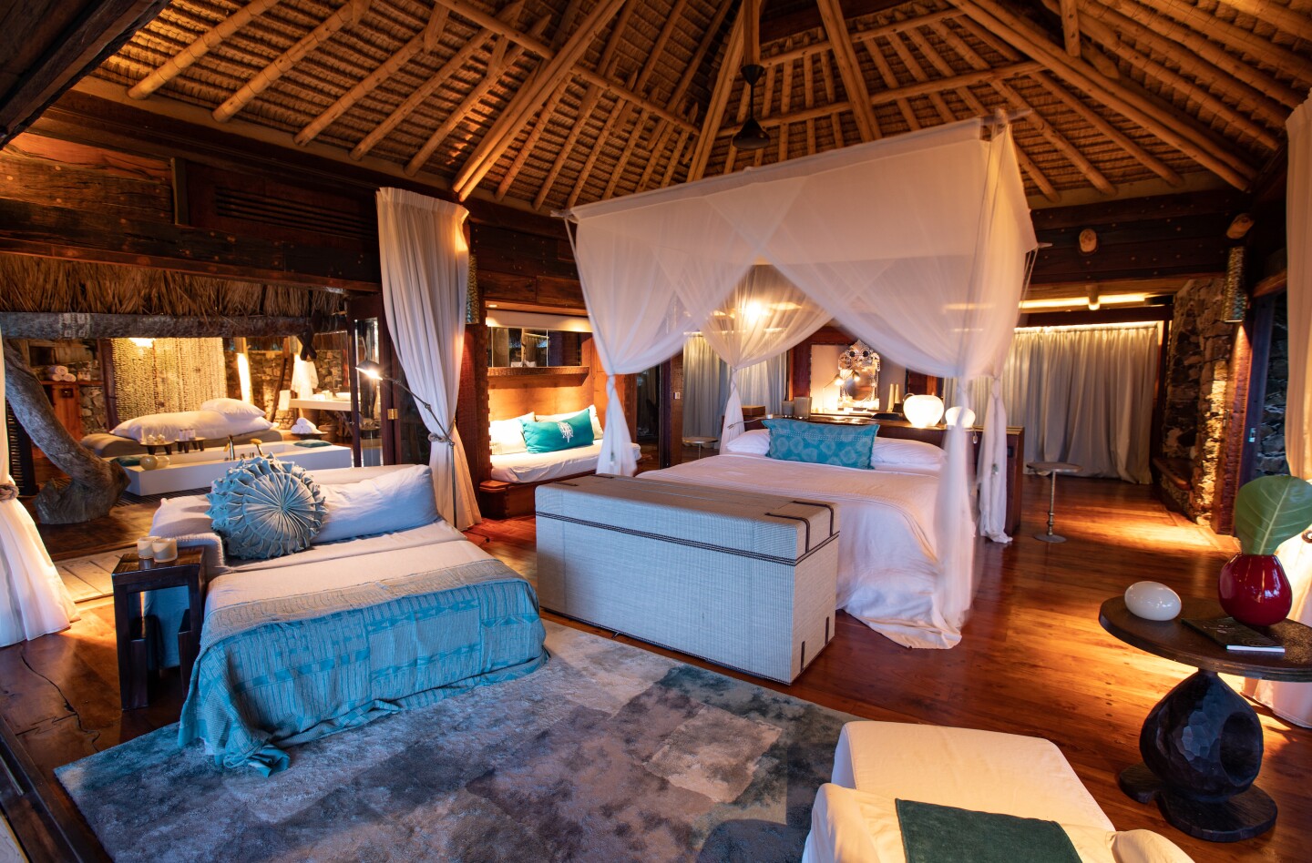 A white canopy bed under a high wooden roof in a private villa