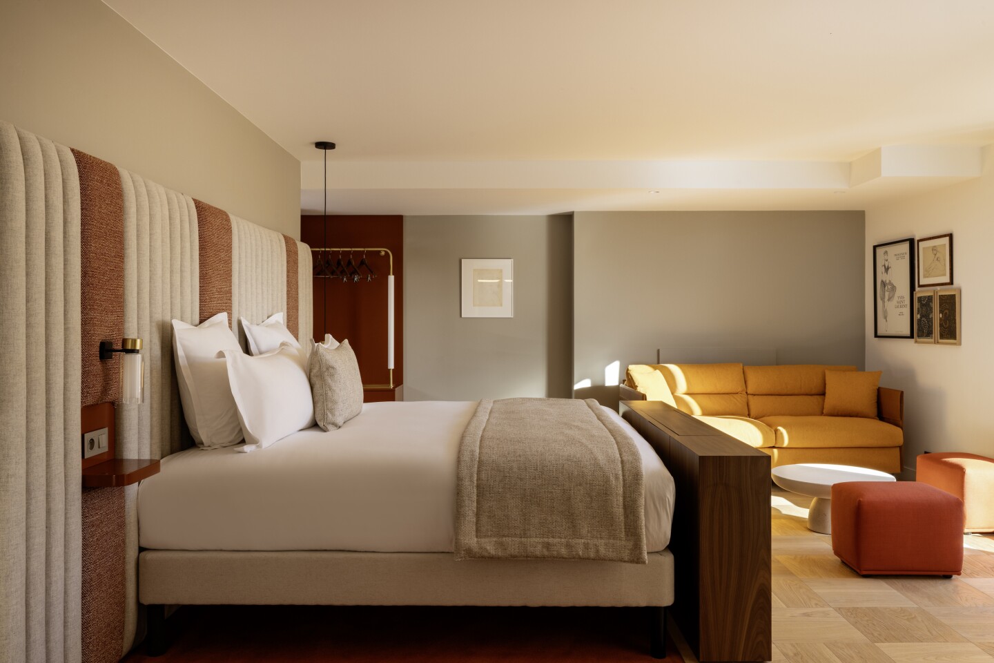 Modern guest room at Hotel Pilgrim in Paris, with mustard sofa and a large brown and white headboard that extends the entire length of a wall