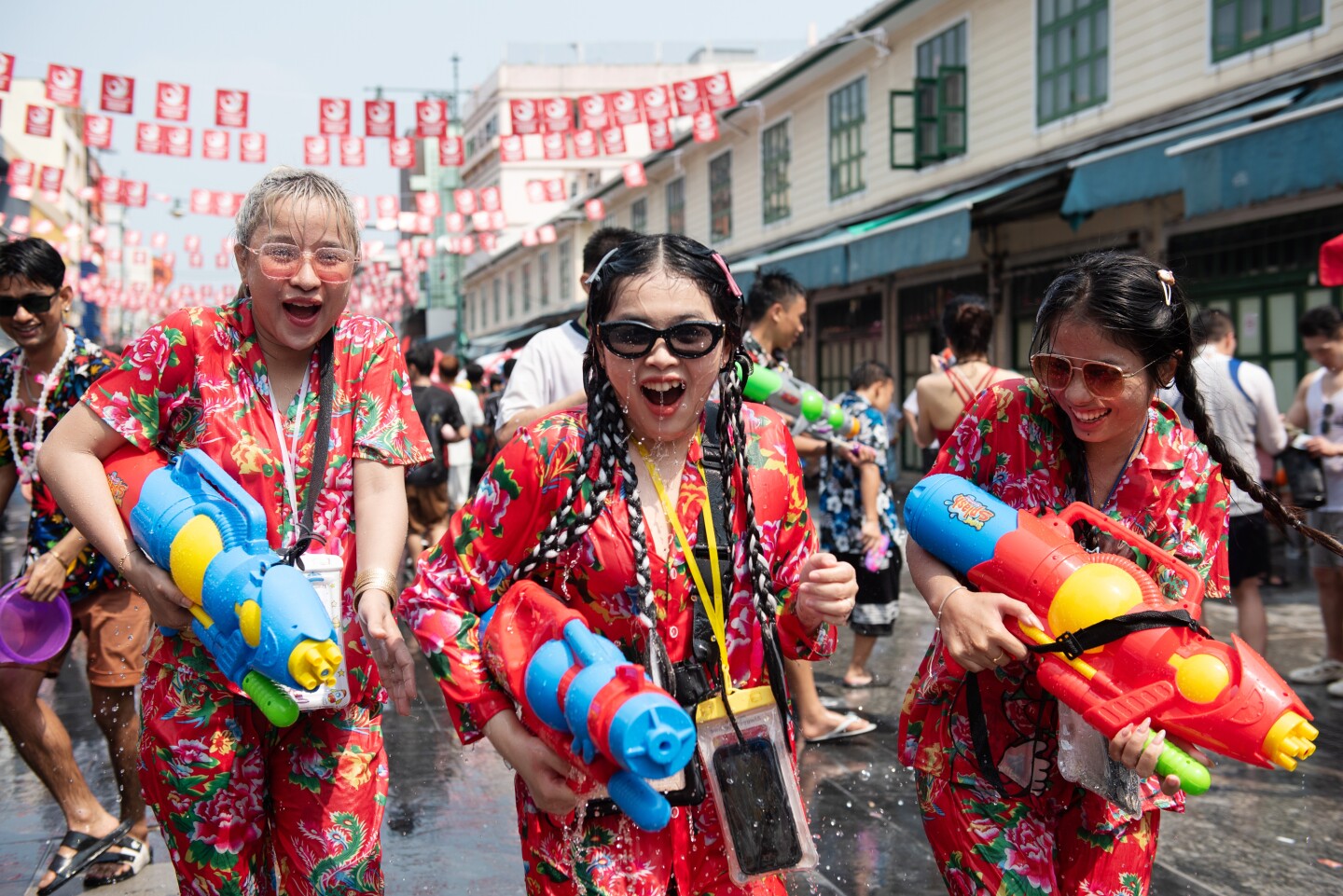 People dressed in red with plastic water guns on street