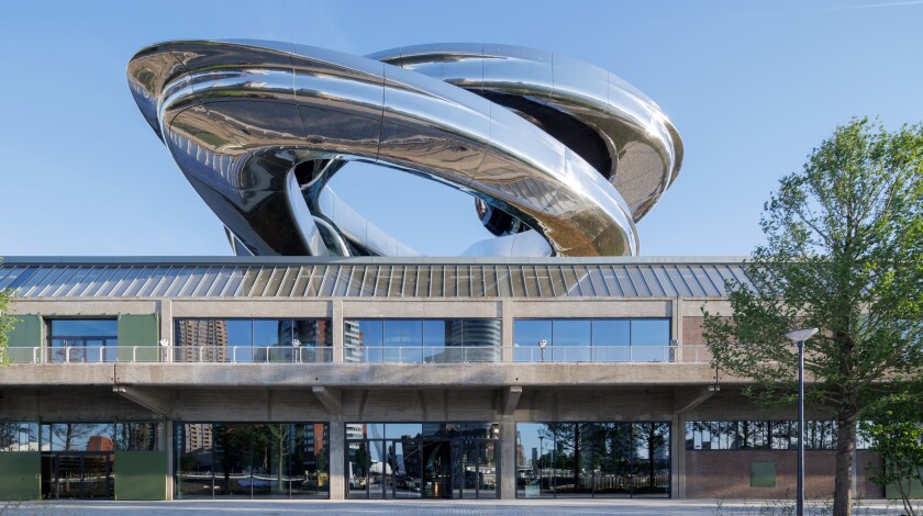 A concrete building with an elaborate steel tornado-shaped staircase stretching above it