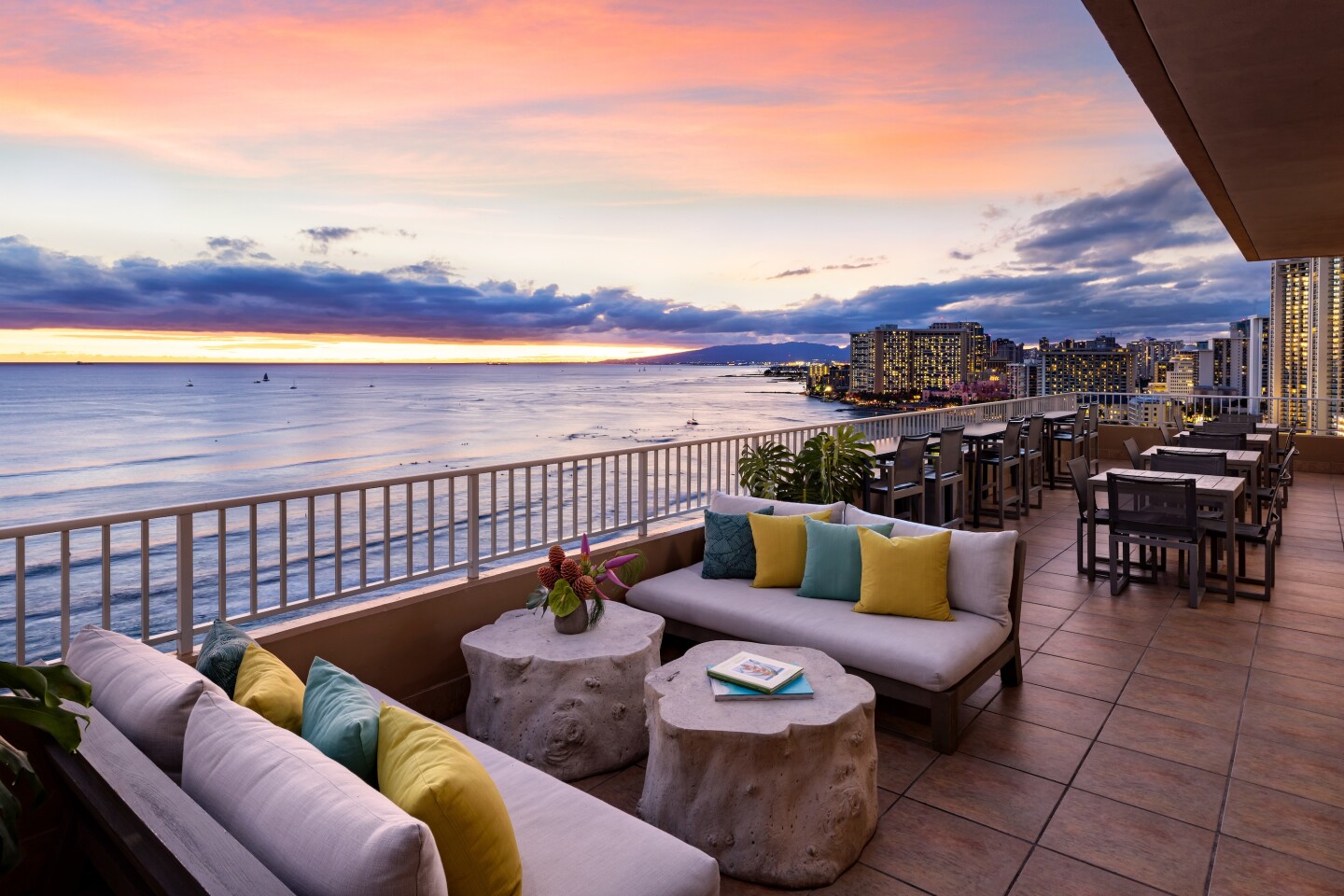 Outdoor terrace of Twin Fin's Coconut Club, with sofas, overlooking Pacific Ocean at sunet