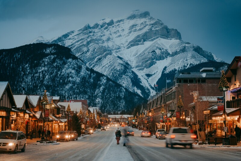 People walking down a wintry early street towards Cascade Mountain in the early evening in the town of Banff in Alberta.