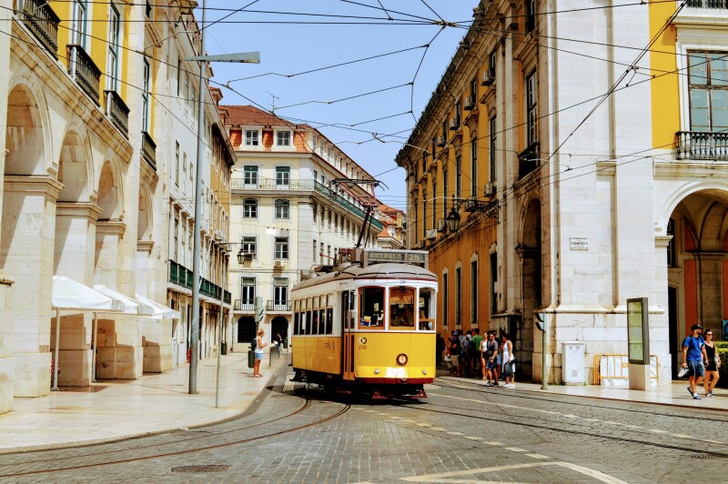 A yellow tram car traveling down a street in Lisbon