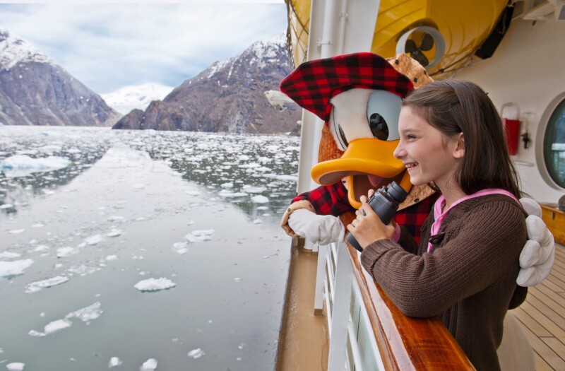 A person in a Donald Duck costume withe their arm around a girl on the deck of a Disney Cruise Line ship in icy Alaskan waters.