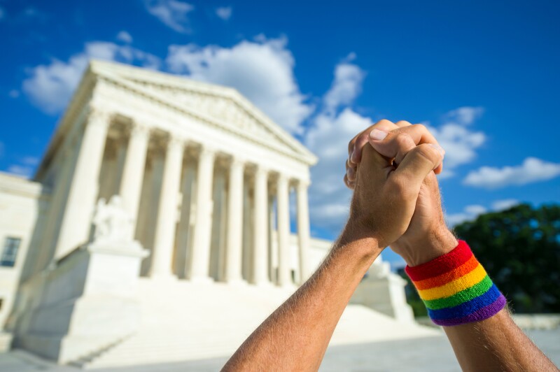 Two hands being held together in a praying motion in front of a Washington D.C. monument