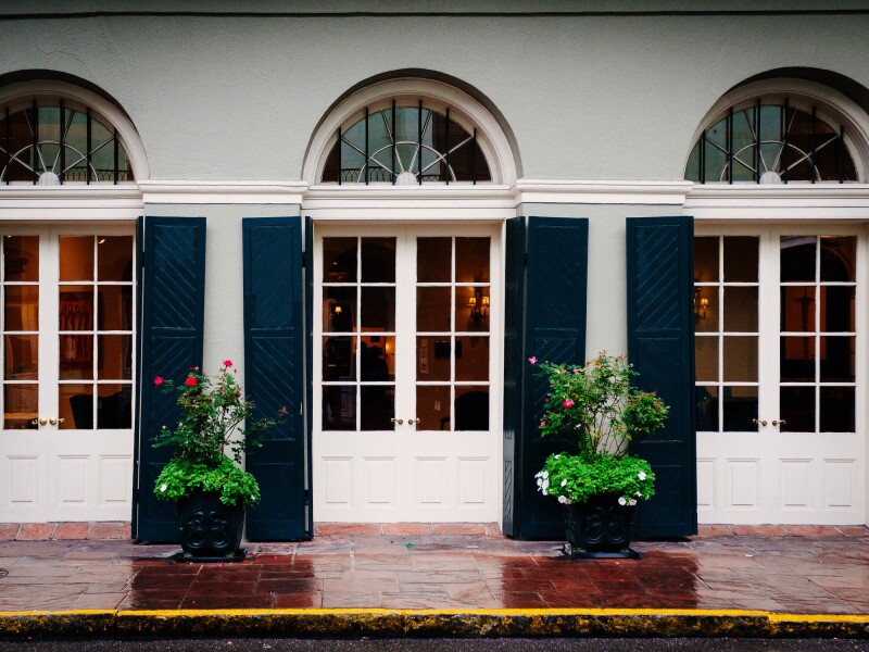 Exterior of Bourbon Orleans Hotel, with three arched doorways with windows, white with dark blue shutters.