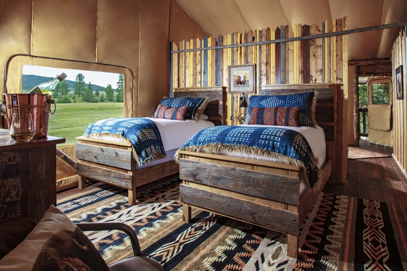 Interior of guest room at the Resort at Paws Up, with black, tan, and white geometric patterned rug and two wood-trimmed beds