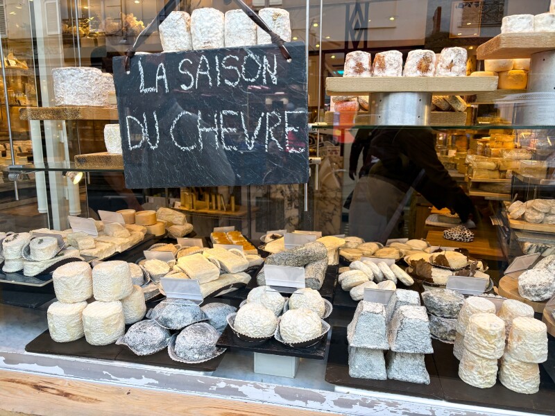 Slate trays of seasonal small goat cheeses on display in a Paris shop window