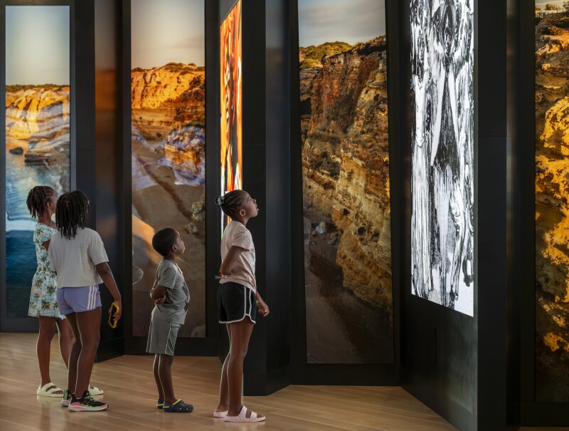 Children looking up at photos of rock formations.