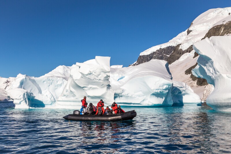 Small groups in Zodiac boats pass icebergs in the Antarctic Peninsula.