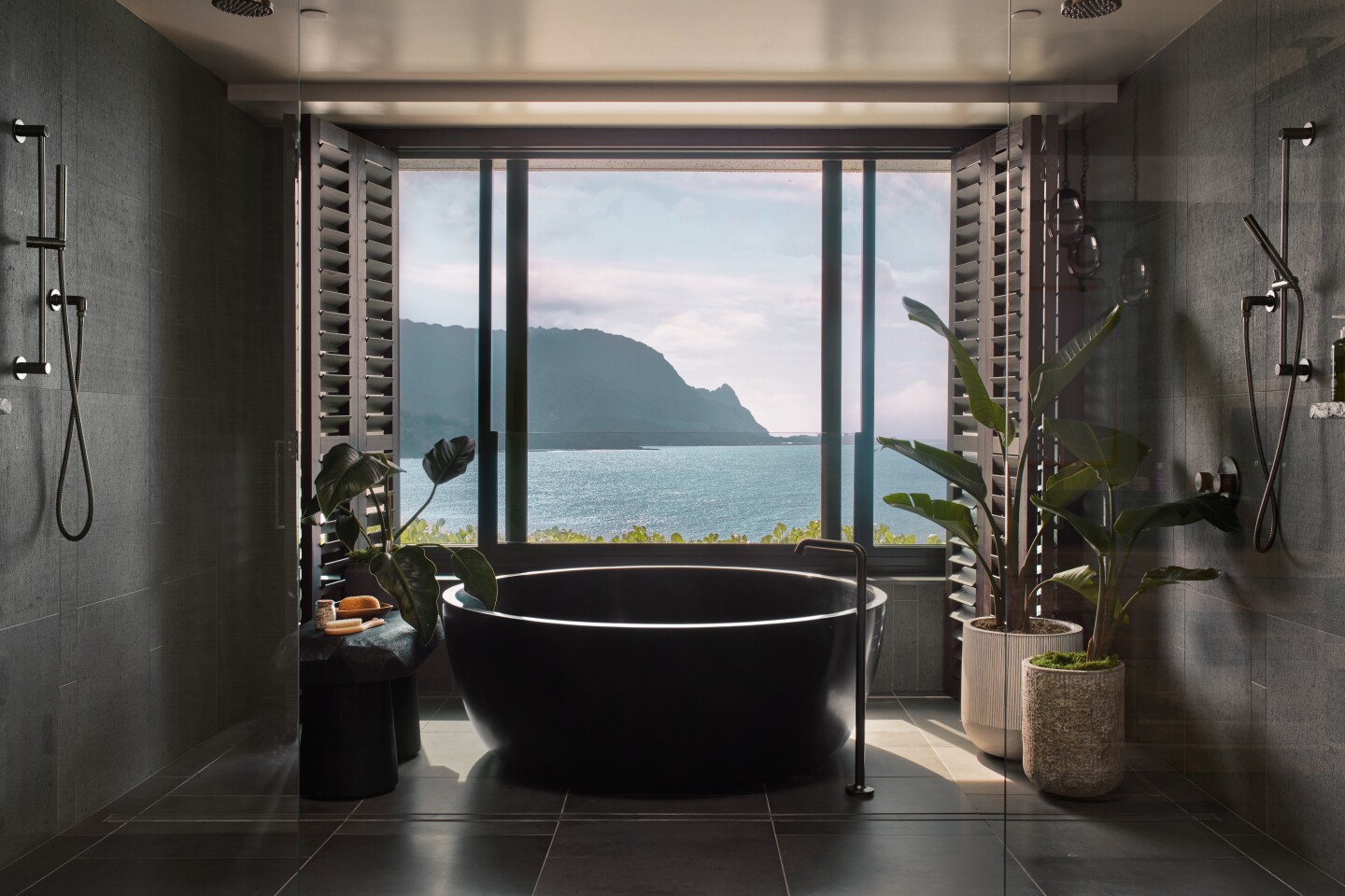 Bathroom in the Napali Penthouse suite, with plants and large round tub beside large window facing the ocean