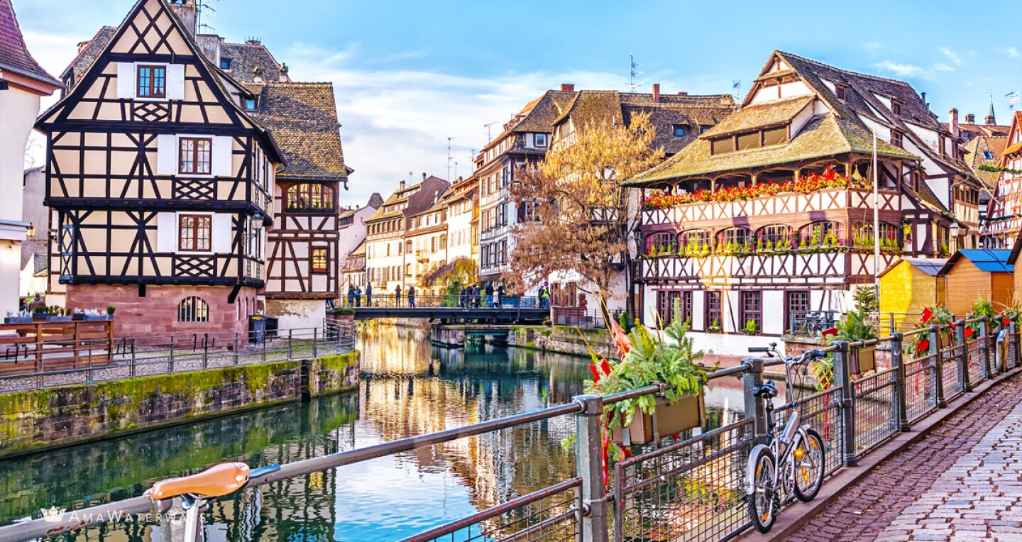 A view from a bridge with a bike on the railing of the river and tall houses in Strasbourg, France