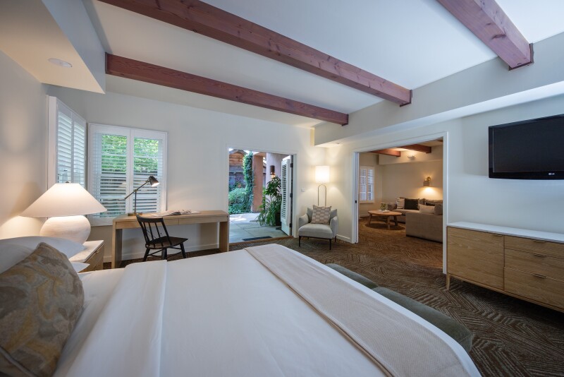 A guest room at Appellation Lodi with a bedroom and separate living area and exposed wooden beams across the ceiling