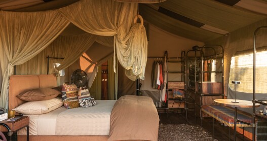 Accommodations at Singita Mara River Tented Camp in Tanzania feature canvas walls and large king-size beds with gauze netting.