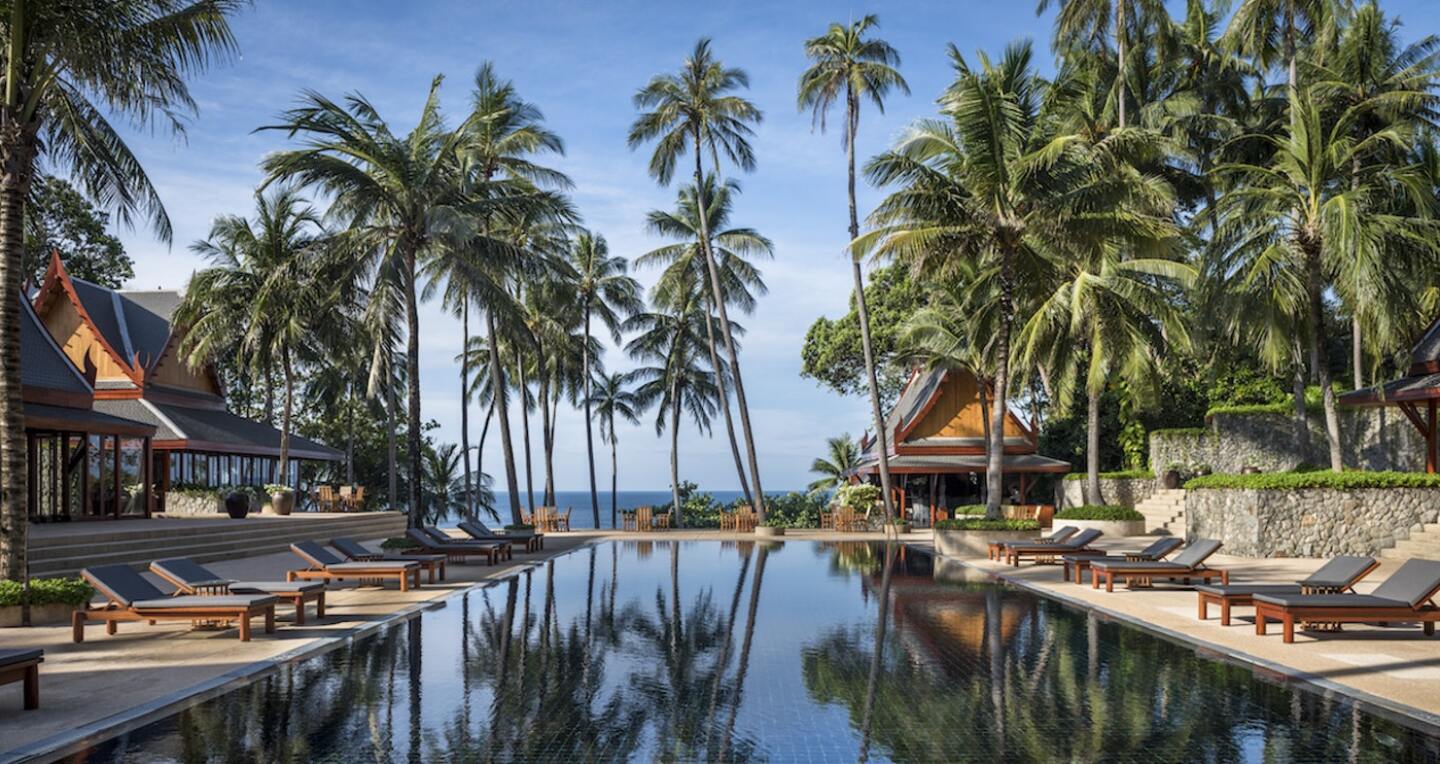 A seaside pool surrounded by palm trees.