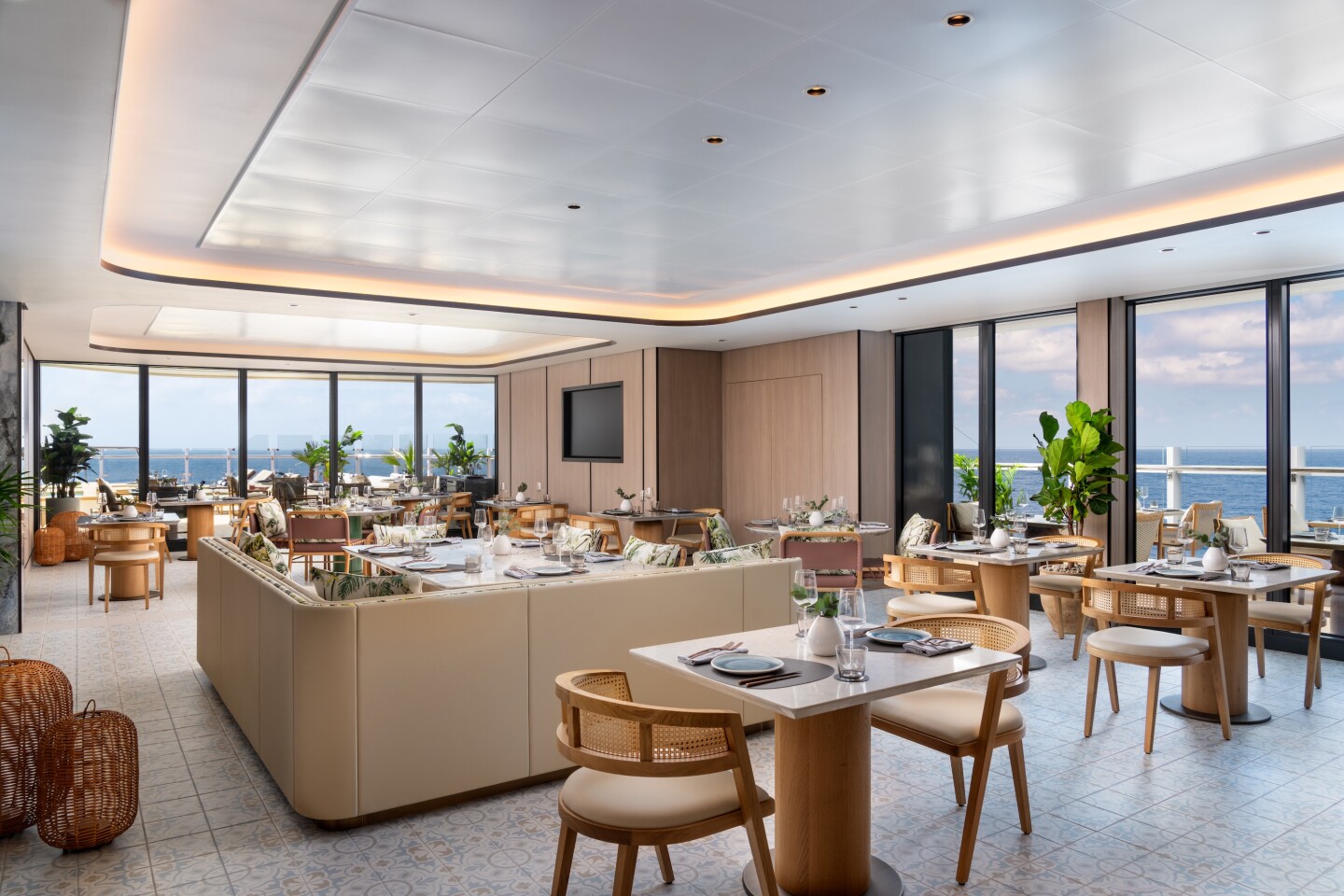 The Beach House dining area on board Ritz-Carlton Yacht Collection's 'Ilma' vessel with large sea-view windows and multiple dining tables and a banquette