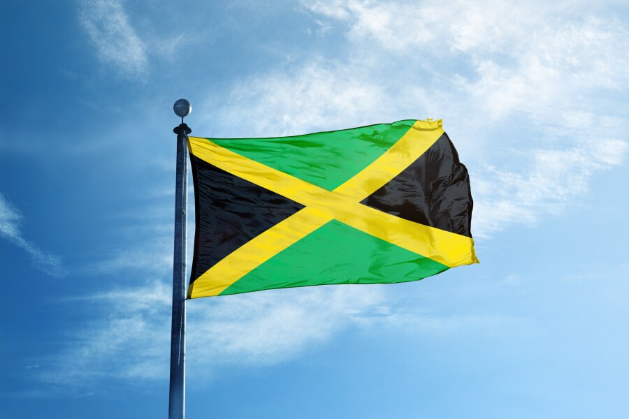 A green, yellow, and black Jamaica flag waving in the sky