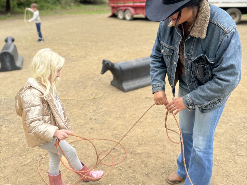 A young girl in pink boots learning how to lasso from a wrangler at Alisal Ranch