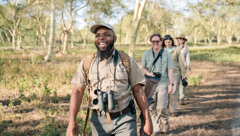 A staff member on a walking safari with guests at Chicari Camp
