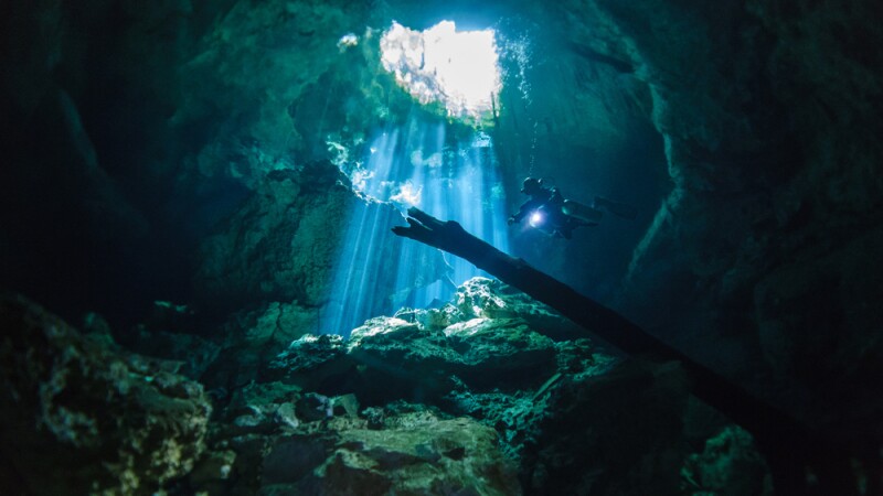 A cave diver wearing sidemount air tanks explores Cenote Tajma-Ha in Mexico