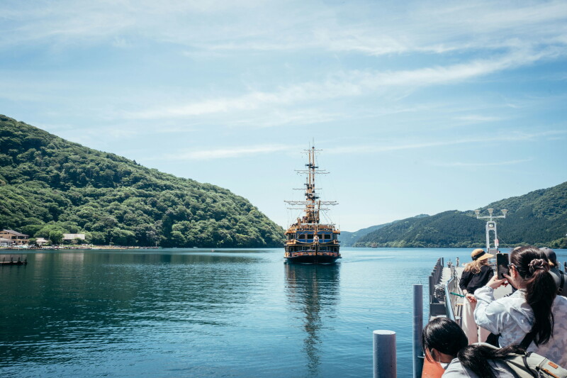 From a pier, tourists take photos of a pirate sightseeing ship on the water.
