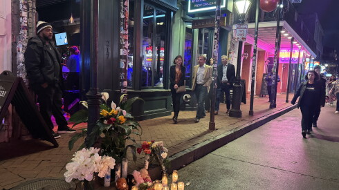 An alter of flowers and candles to one of the victims of the New Year's Day attack is set up curbside on Bourbon Street in New Orleans as people are walking about
