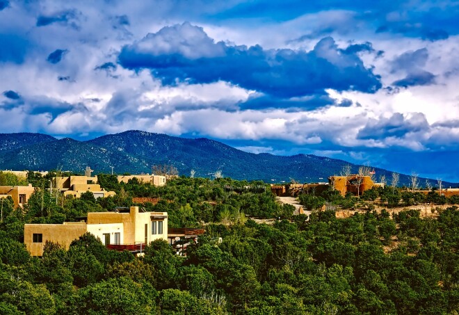 modern adobe-style homes dotted among the green trees and mountains by Santa Fe