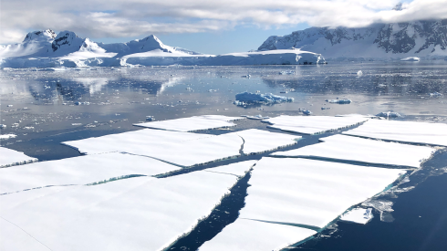 An image of the seas of Antarctica with snow-capped mountains in the background and ice floes in the foreground.