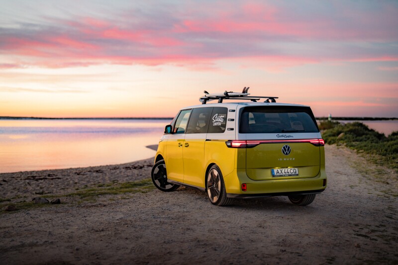 Yellow Volkswagen electric vehicle on a road near water during sunset.