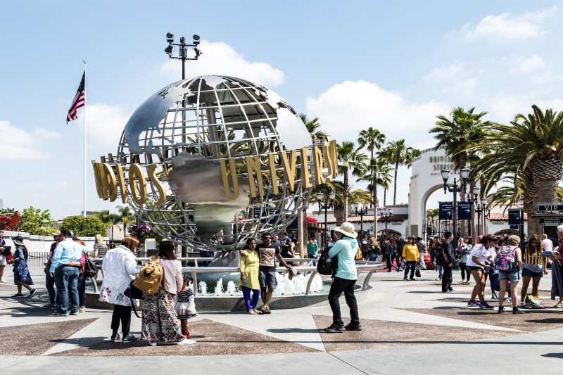 People around a globe statue with the words "Universal Studios" wrapped around it