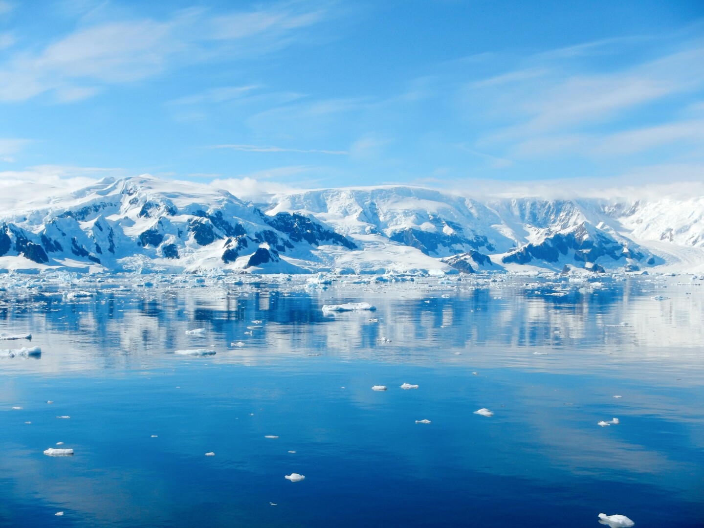A blue lake with snow-covered mountains in the background