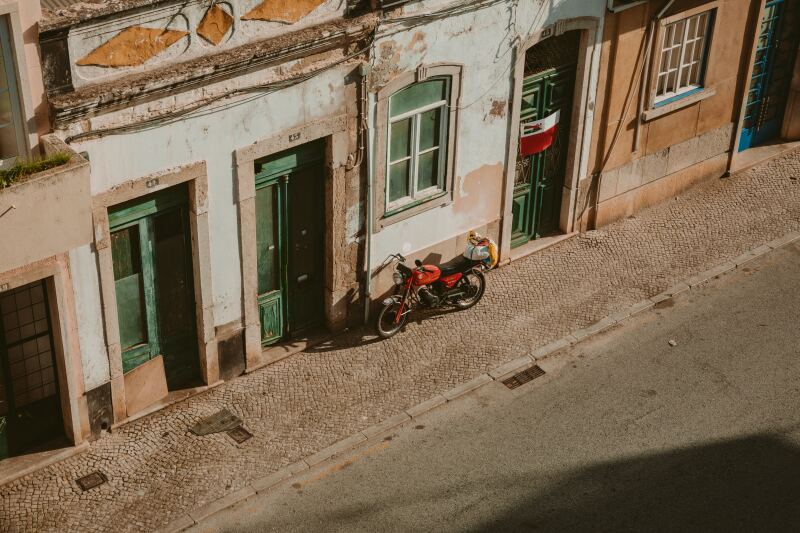 A view of some older buildings and a red motorcycle on the street in Faro, Portugal