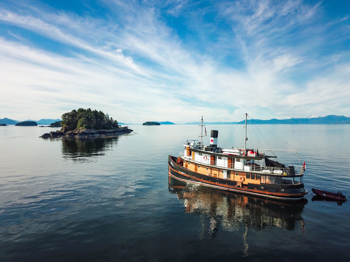 Maple Leaf Adventures' 12-person tugboat in calm water with a small island nearby