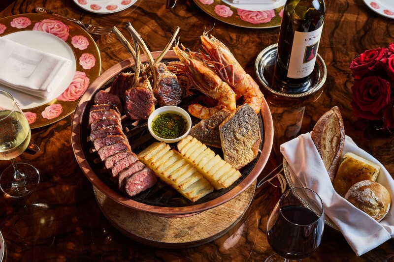 Round platter of charcuterie, with basket of bread and bottle of wine