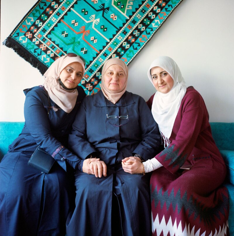 Lobna Helli (right), the chef- owner of Lazord, sits with her mother, Noha (center), and sister, Randa (left), beneath the restaurant’s signature tapestry.